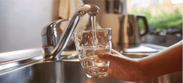 vattenglas som fylls av rent rinnande kranvatten